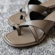 Pair of beige sandals with black straps on a textured surface